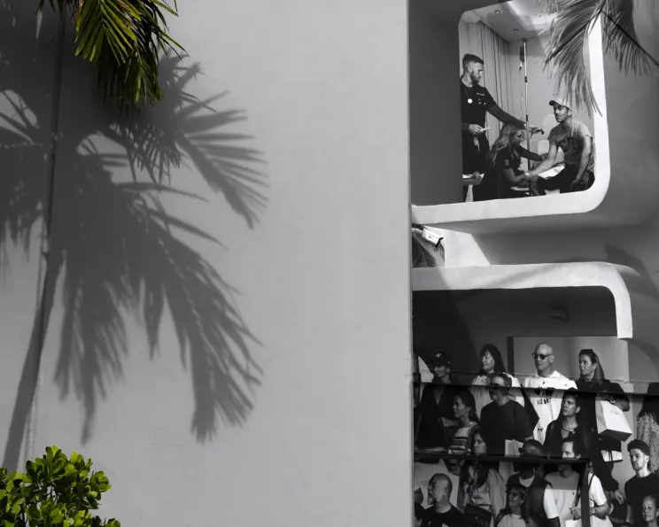 Black and white photo of people in modern building balconies, sunny day.