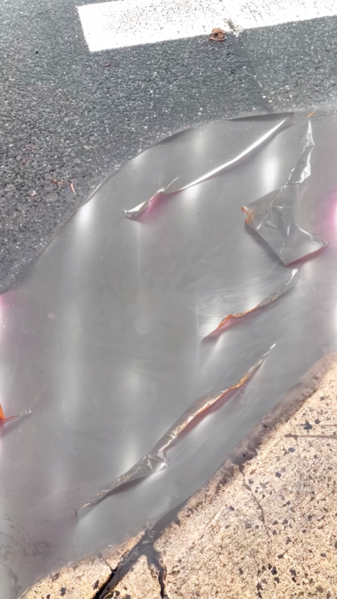 Close-up of a digital, liquid reflective surface on asphalt.