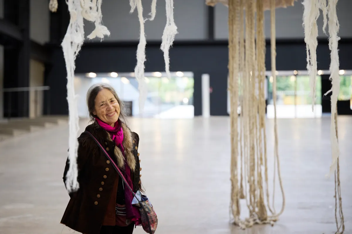 An artist stands confidently next to their large-scale art installation.