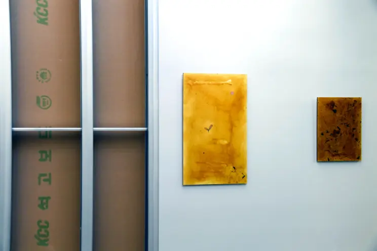 Three art pieces displayed on a wall: a large window frame installation with cardboard behind the glass, a medium-sized ab...