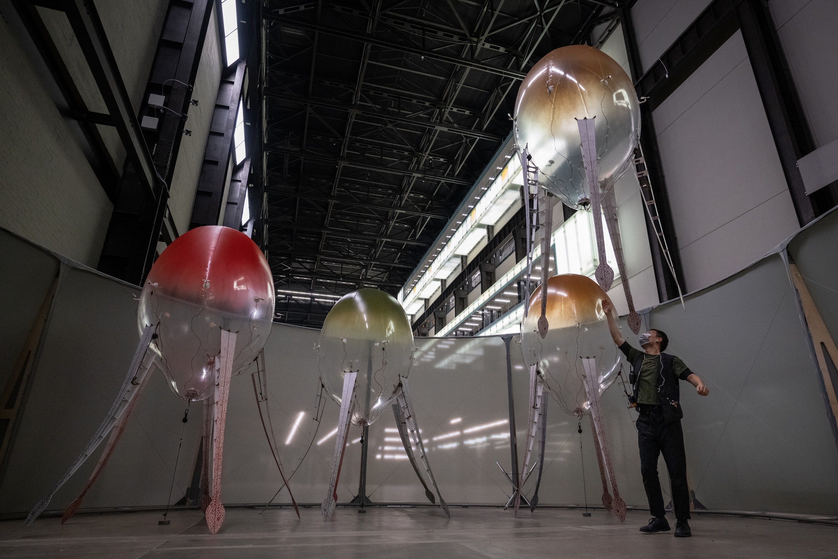A person busily setting up a series of elaborate ceiling lamps, each intricately designed to resemble an octopus with tent...