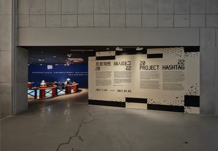Event poster featuring the text 'PROJECT HASHTAG 2022' on display in a museum space.