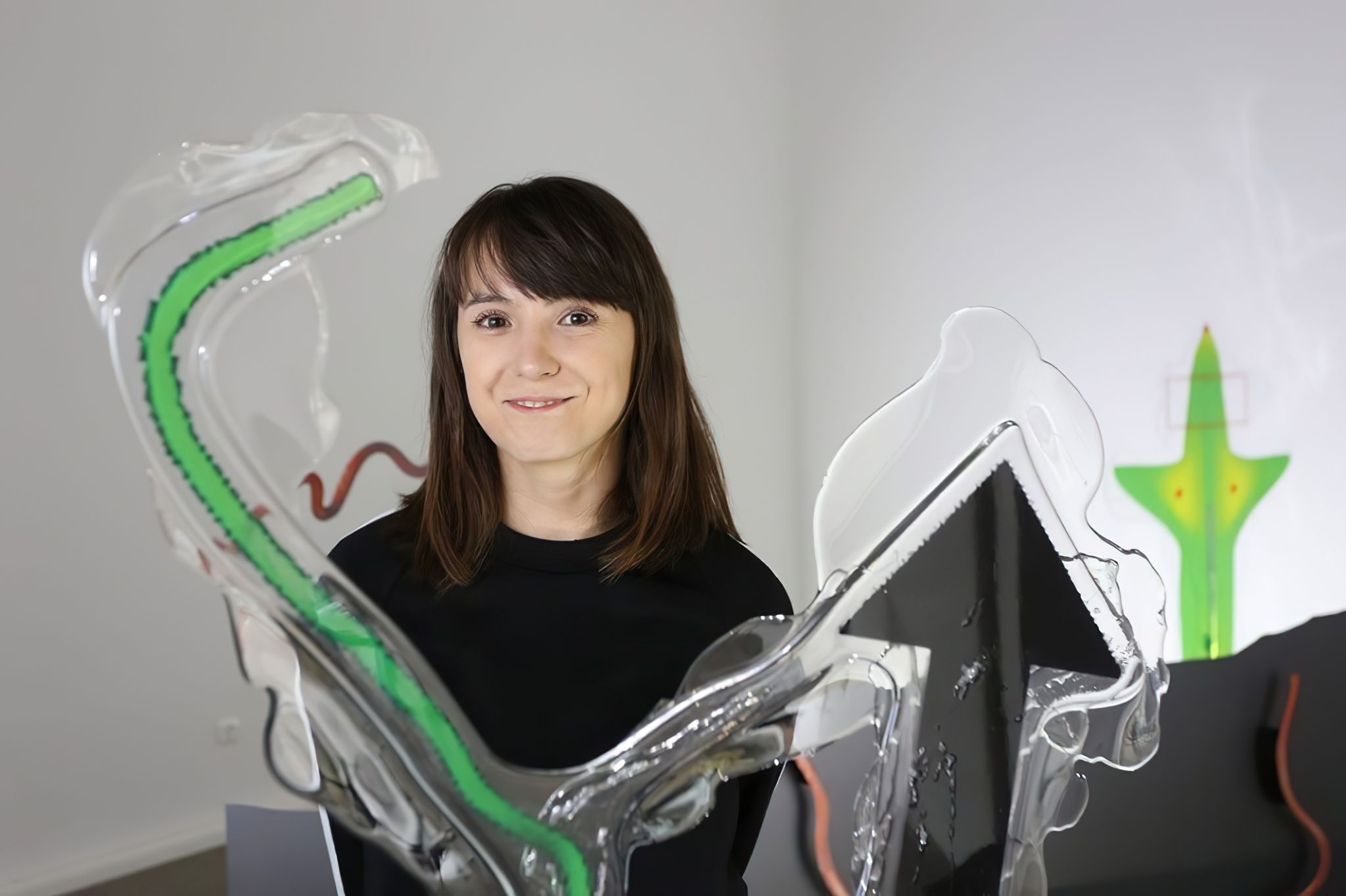 A smiling person posing in front of transparent, curvy forms adorned with colorful drawings.