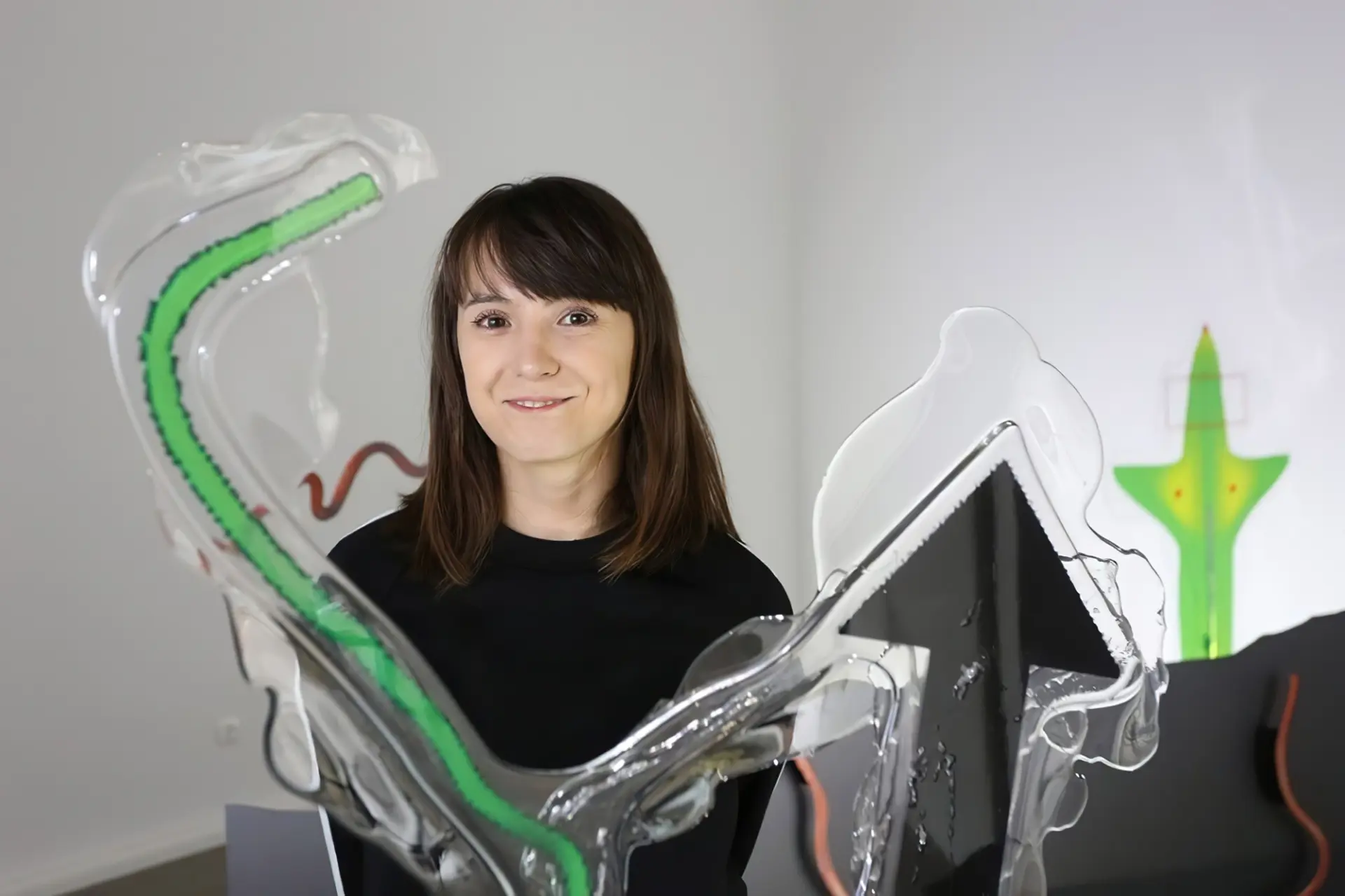 A smiling person posing in front of transparent, curvy forms adorned with colorful drawings.