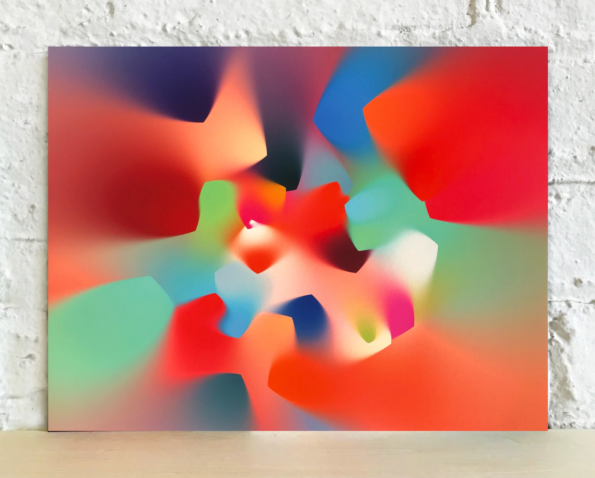 A smudged, kaleidoscopic print leaning against a wall, featuring gradient swirls of color.