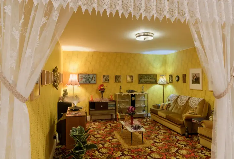 A cozy, homey front room with warm yellow walls. Space includes a comfortable sofa, and additional living room furniture arranged neatly.