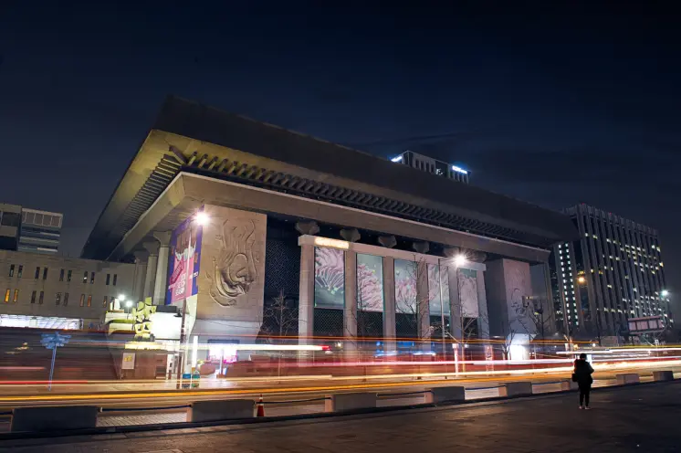 Nighttime cityscape showcasing a long-exposure shot of a building with streaking light trails.