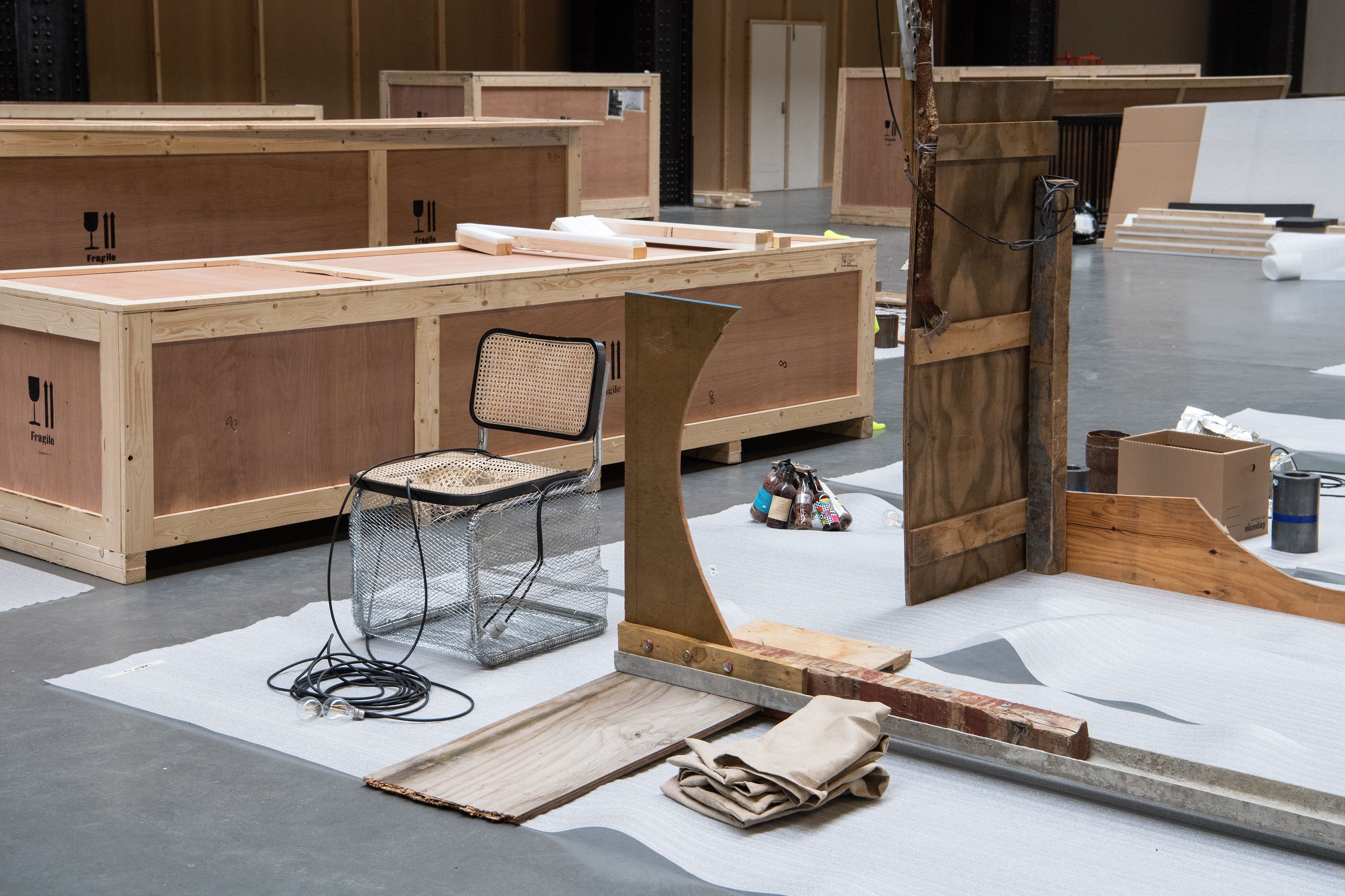 Wooden transport containers arranged in a room, with an art installation being created near them.