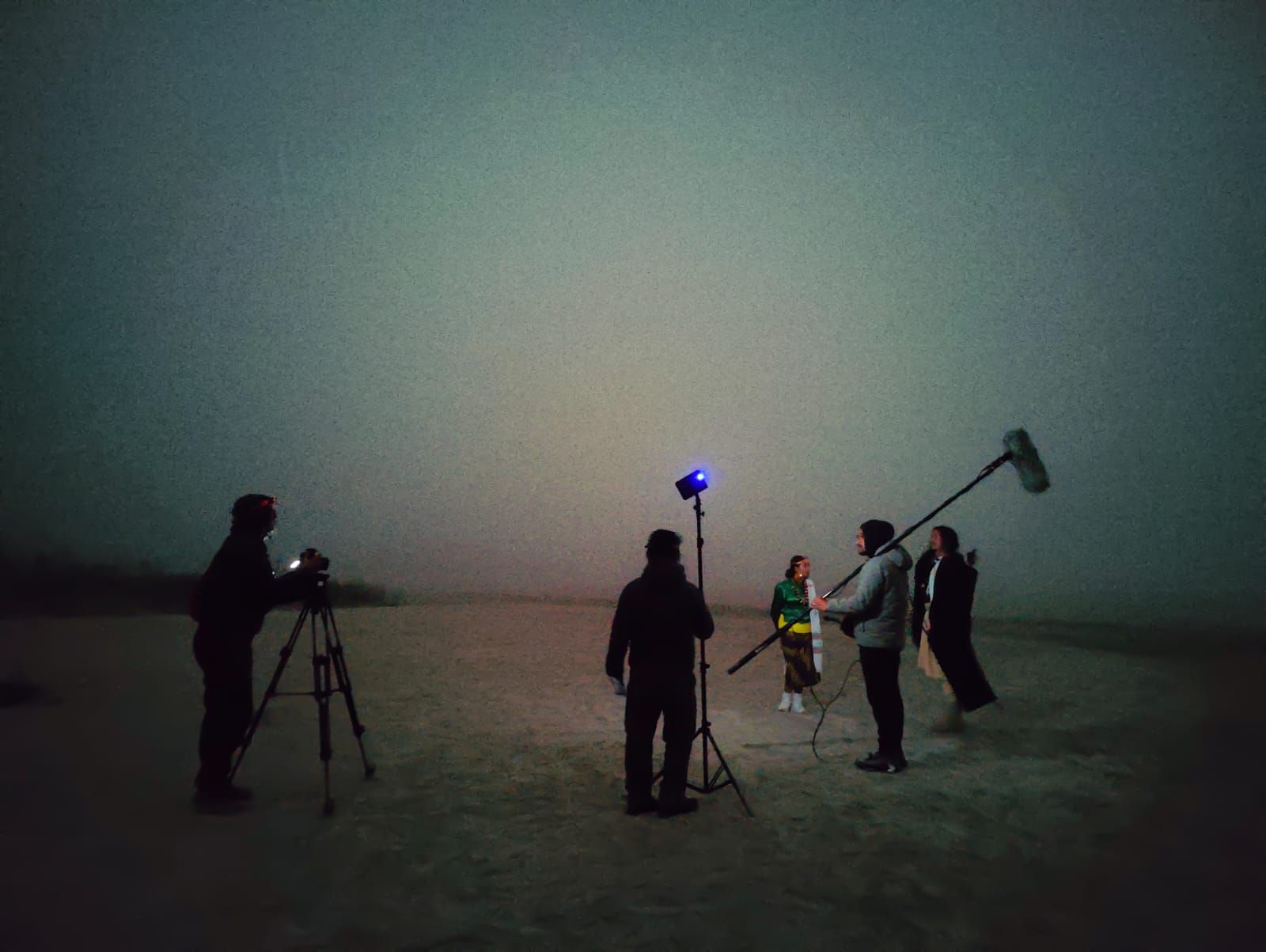 A filming team is at work in a field. The crew, equipped with professional video equipment, is focused on capturing a scen...