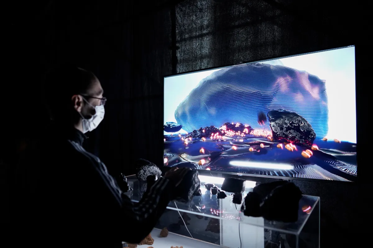 A person engaging with a digital game displayed on a large screen, set against a dark background.