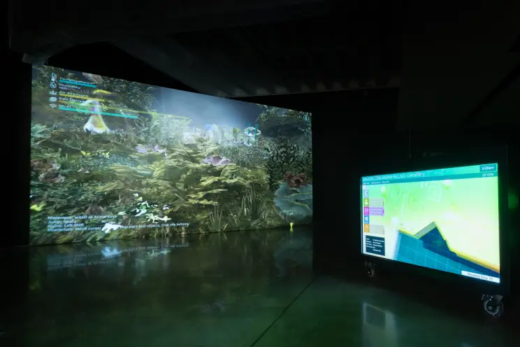 Digital art installation displaying a lush virtual garden on a large screen, with a mobile monitor showing a 2D map layout.