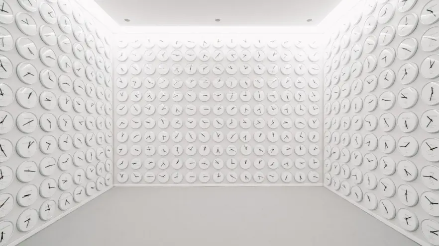 A room with walls entirely adorned with round white clocks. Each clock displays a different time, indicative of various gl...