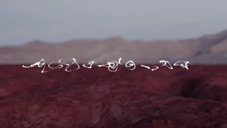 White abstract line formations floating above a reddish desert landscape with mountains in the distance.