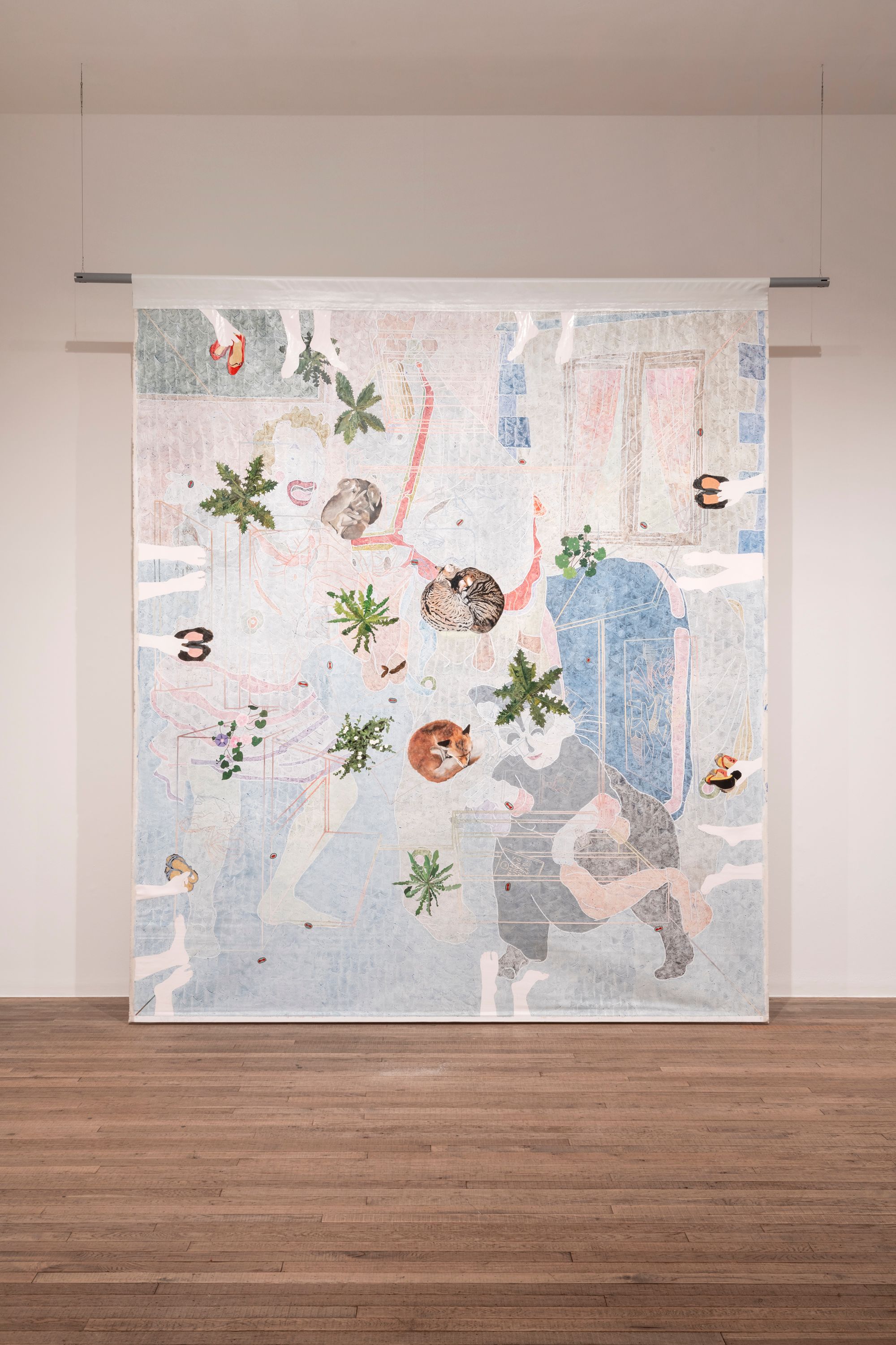 An abstract tapestry artwork featuring human and plant forms, suspended in a gallery with a wooden floor.