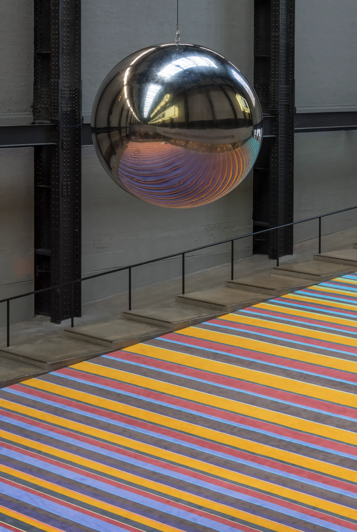 A large sphere hangs above a floor featuring a design of multicolored lines.