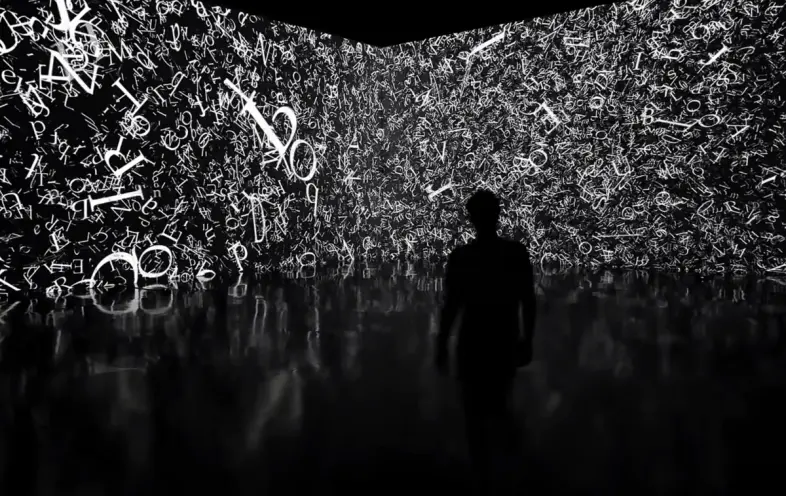 A silhouette of a person stands in a dimly lit room, facing a long, black room divider filled with white letters styled in...