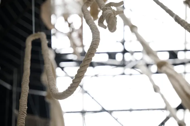 Close-up photography of a intricately woven rope, part of an art installation, with a blurred background of the exhibition...