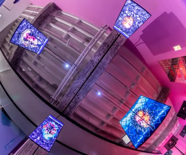 Overhead view of monitors with intricate designs, hanging from a ceiling.