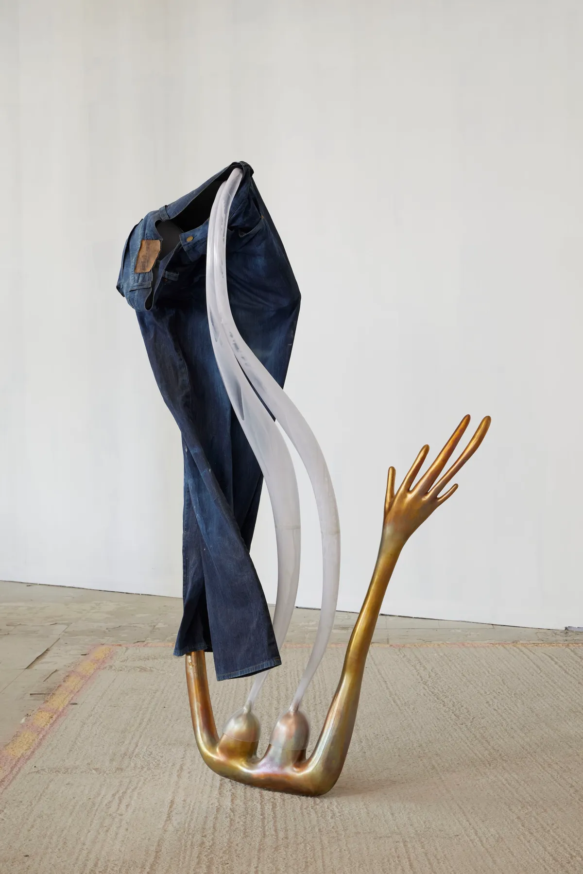 Art sculpture resembling a human limb, draped by a pair of blue jeans.