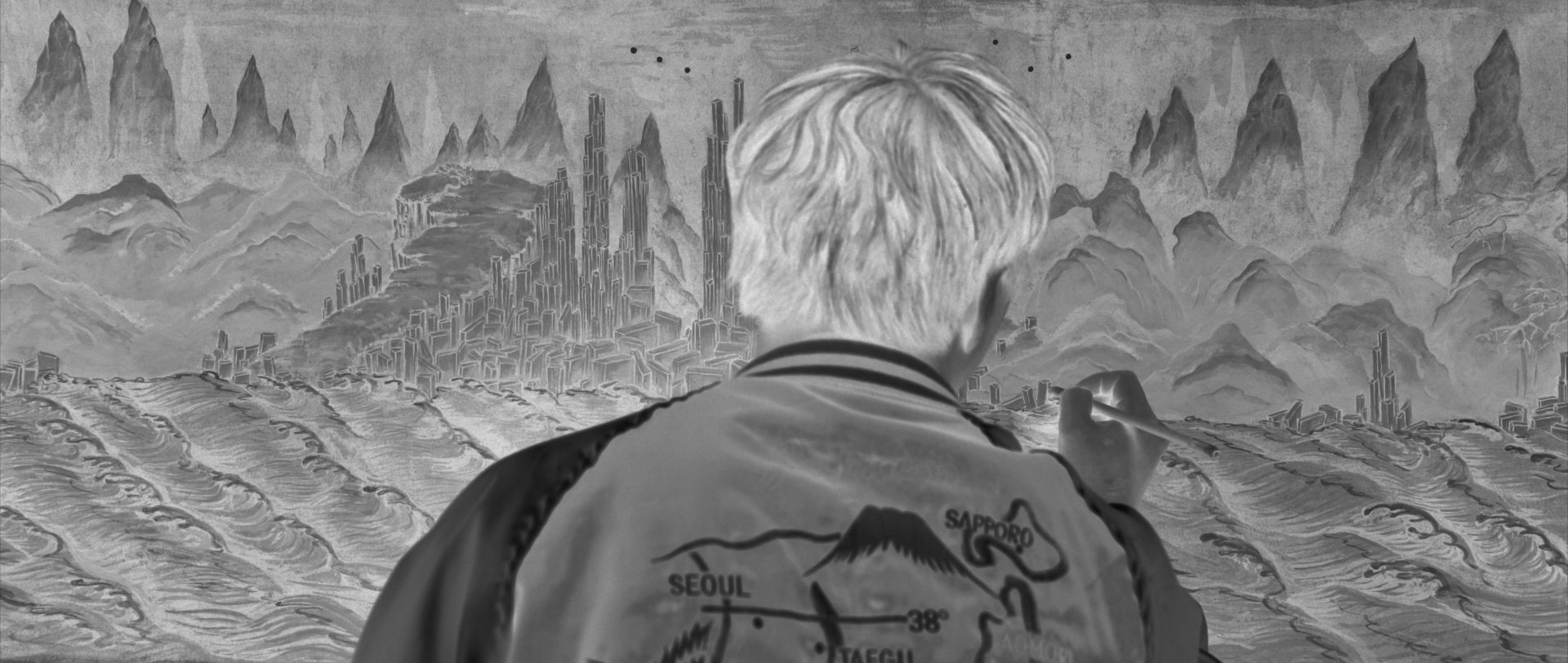A monochrome reversed image displaying a person meticulously drawing a detailed seascape.