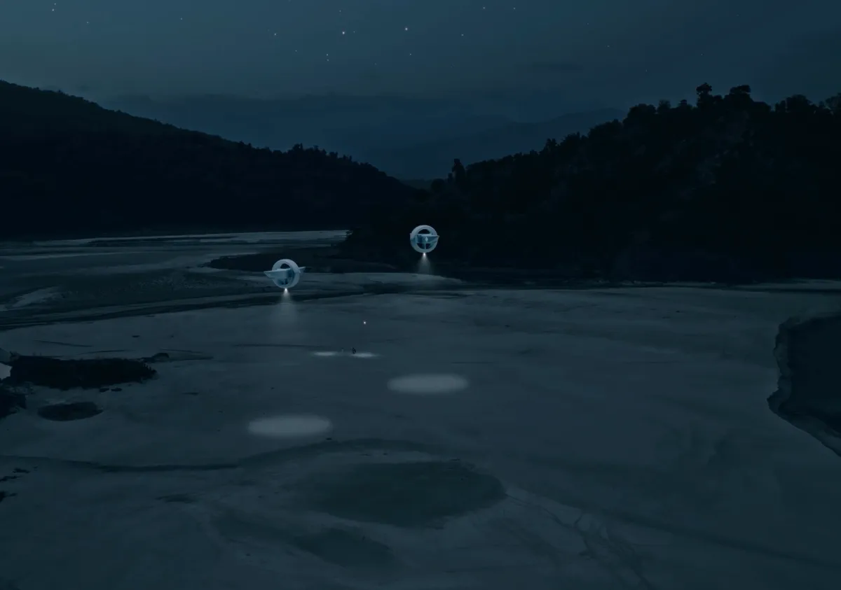 A nighttime landscape of rolling hills with two futuristic drones casting light onto a riverbed or pathway.