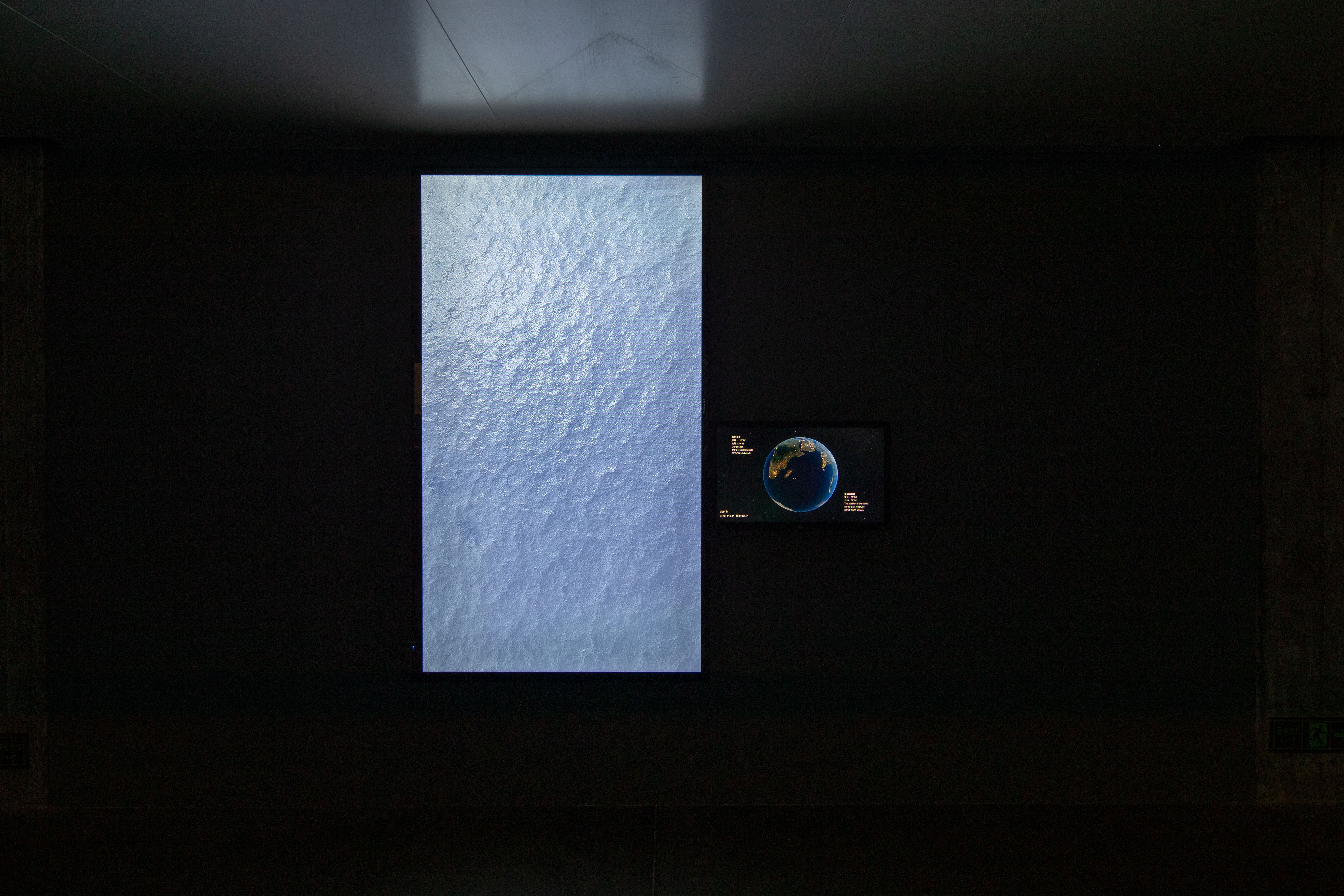A video art installation showing a large ocean wave with a small Earth image.