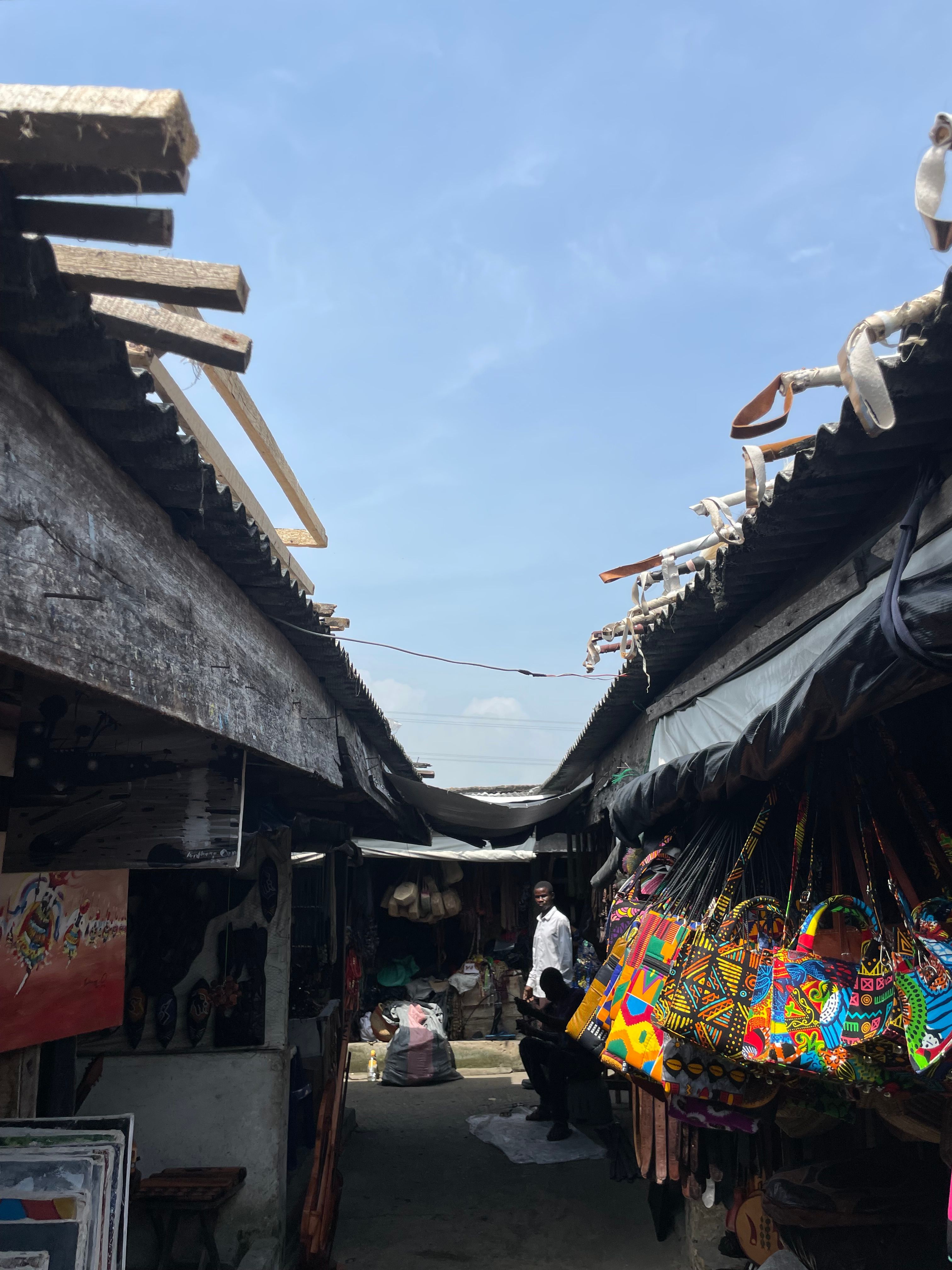A bustling traditional market alleyway with colorful bags and handmade items.