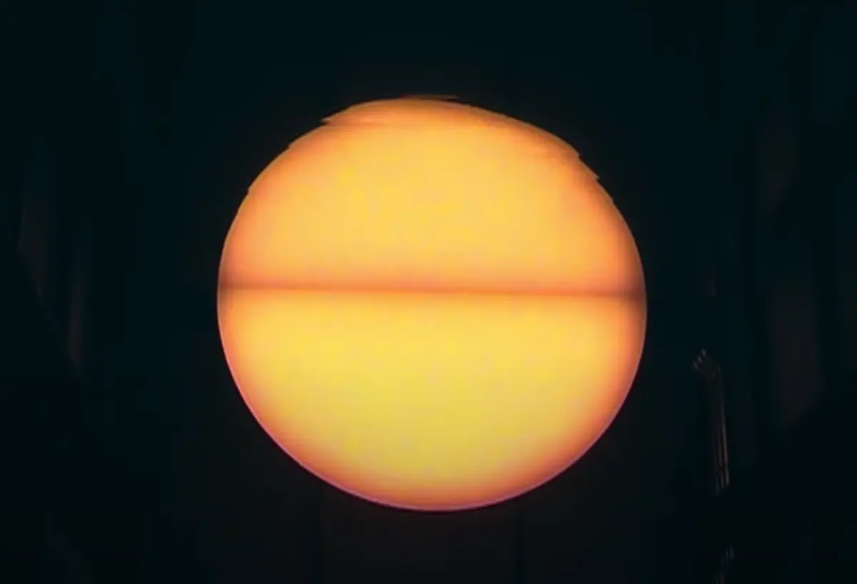 A bright yellow ball, reminiscent of the sun, stands out prominently against a stark black background.