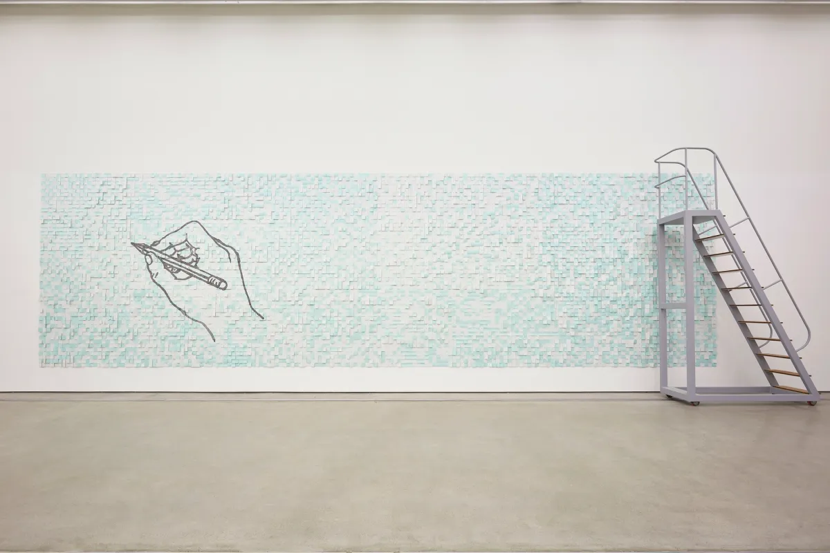 A wide rectangular mosaic art piece in aqua blue, featuring a drawn hand holding a pencil on the left. A silver metal ladder rests on the right side.