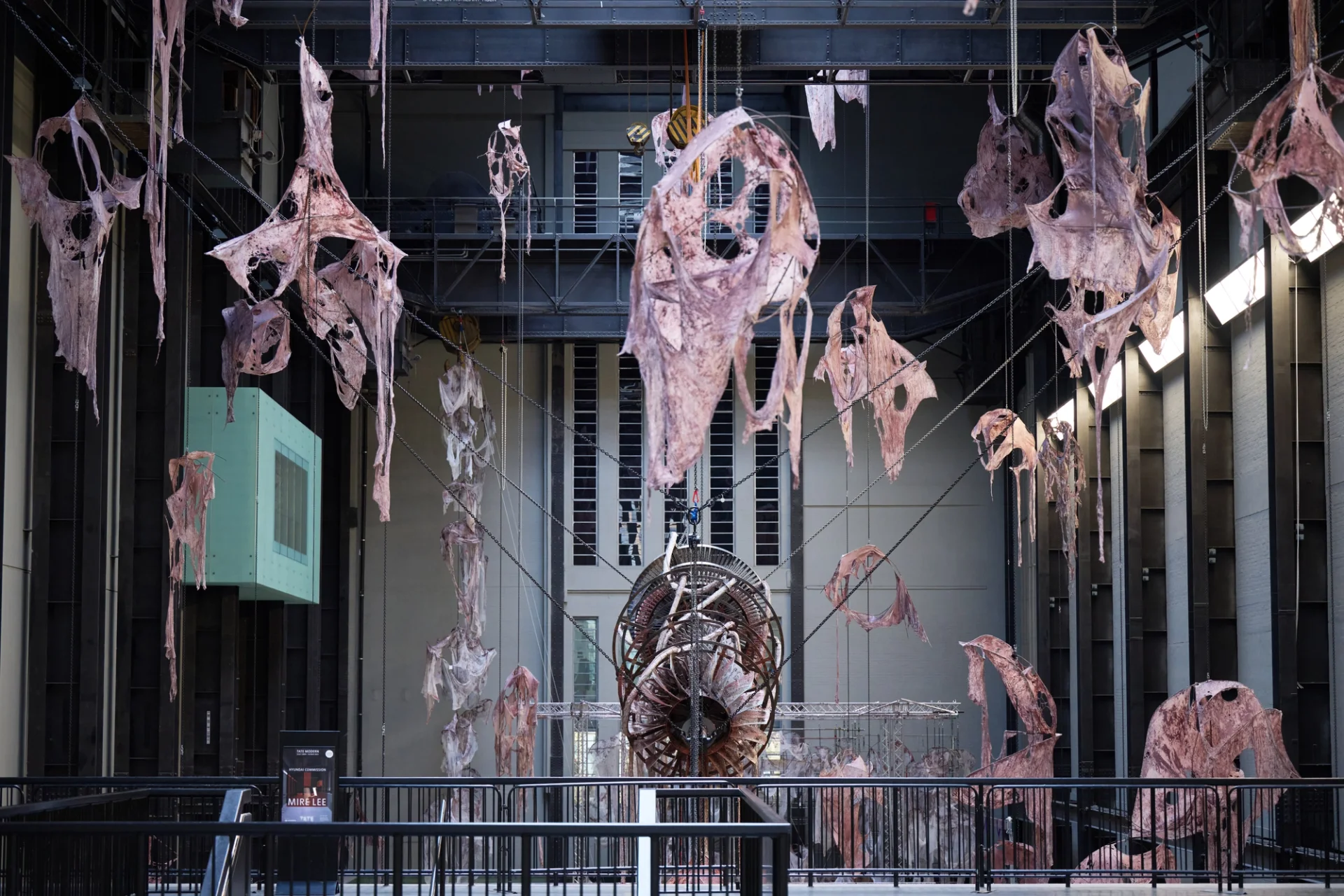 Close-up of abstract organic forms and mechanical structures suspended in an industrial gallery space.