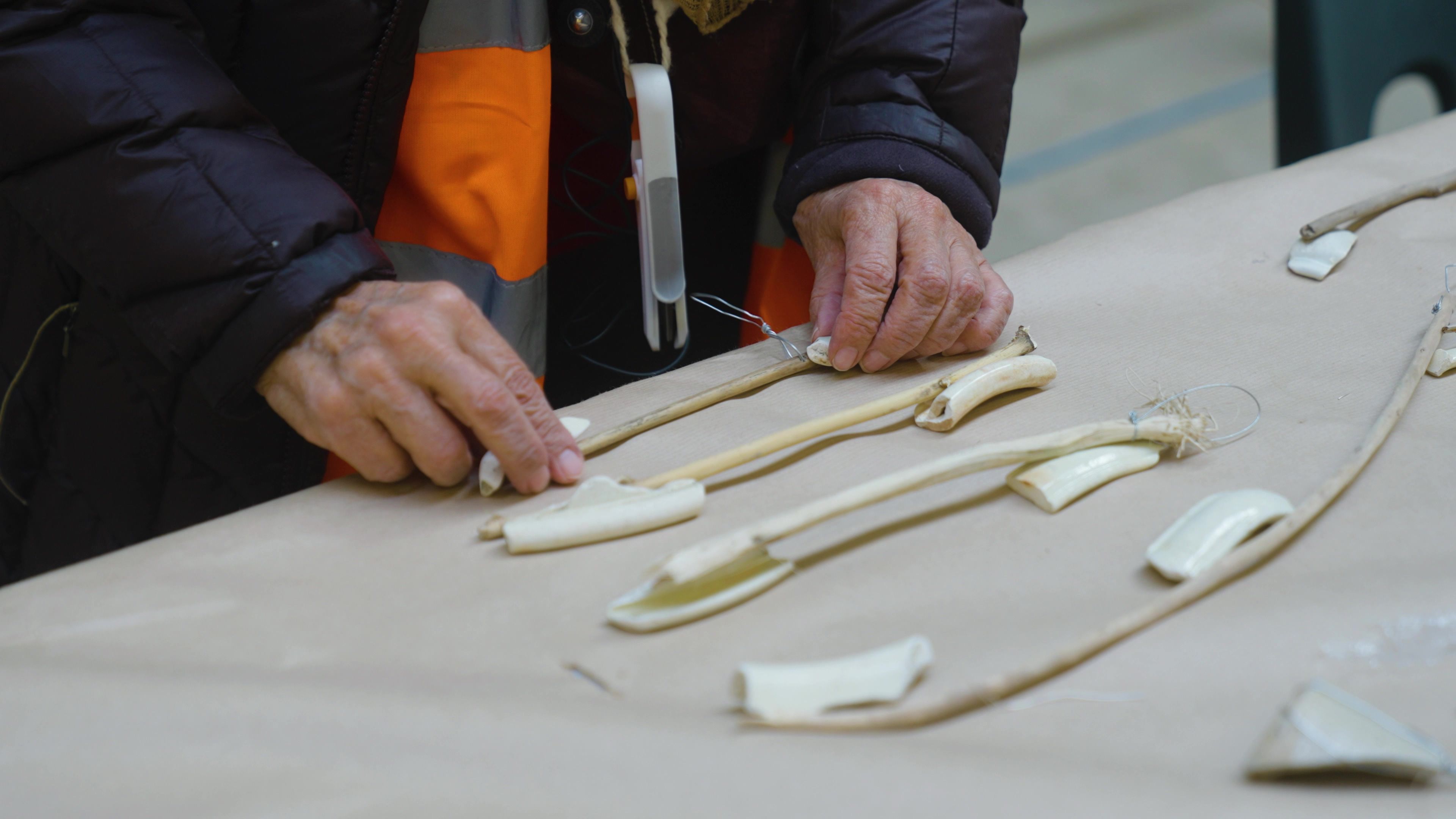 Hands interacting with various beige fragments placed on a table.