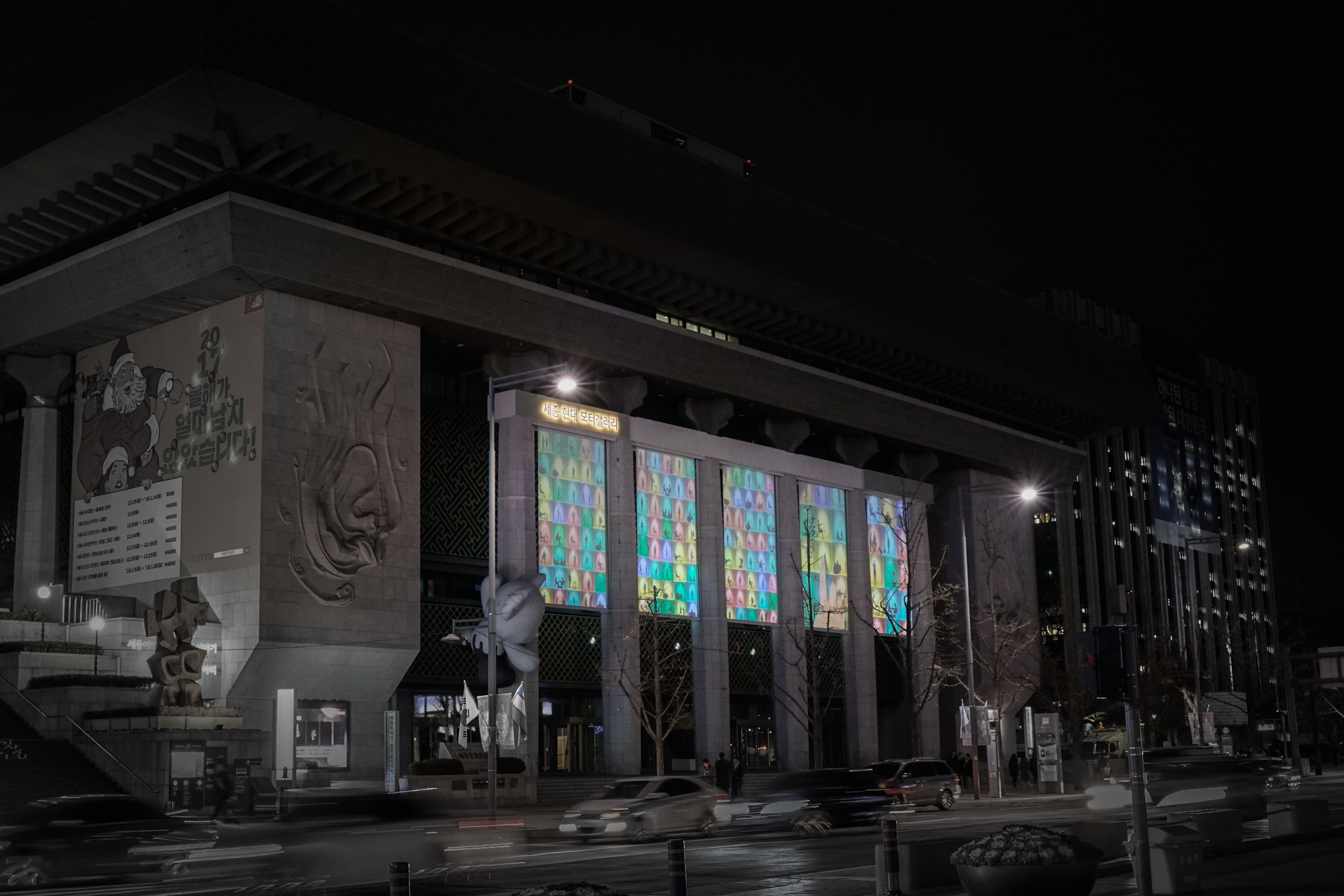 A building facade with architectural pillars, illuminated with pastel-colored images.