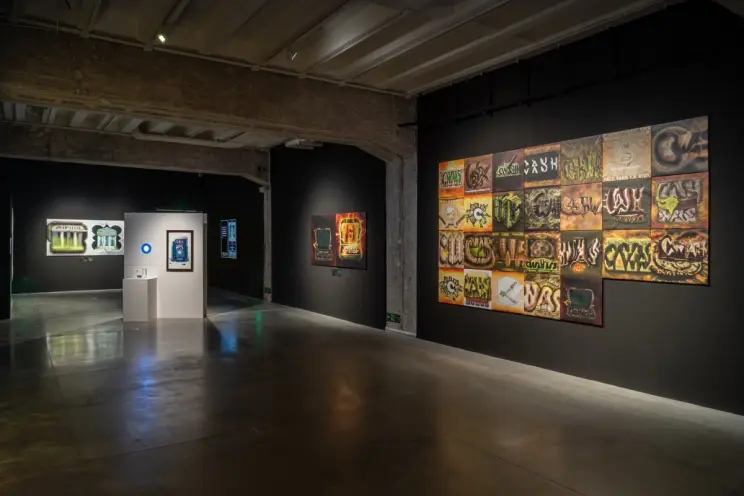 Gallery view showing colorful wall art and a single bright exhibit centerpiece.