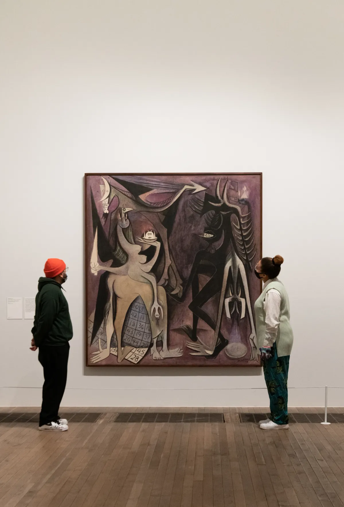 Two individuals observing a painting in a gallery.