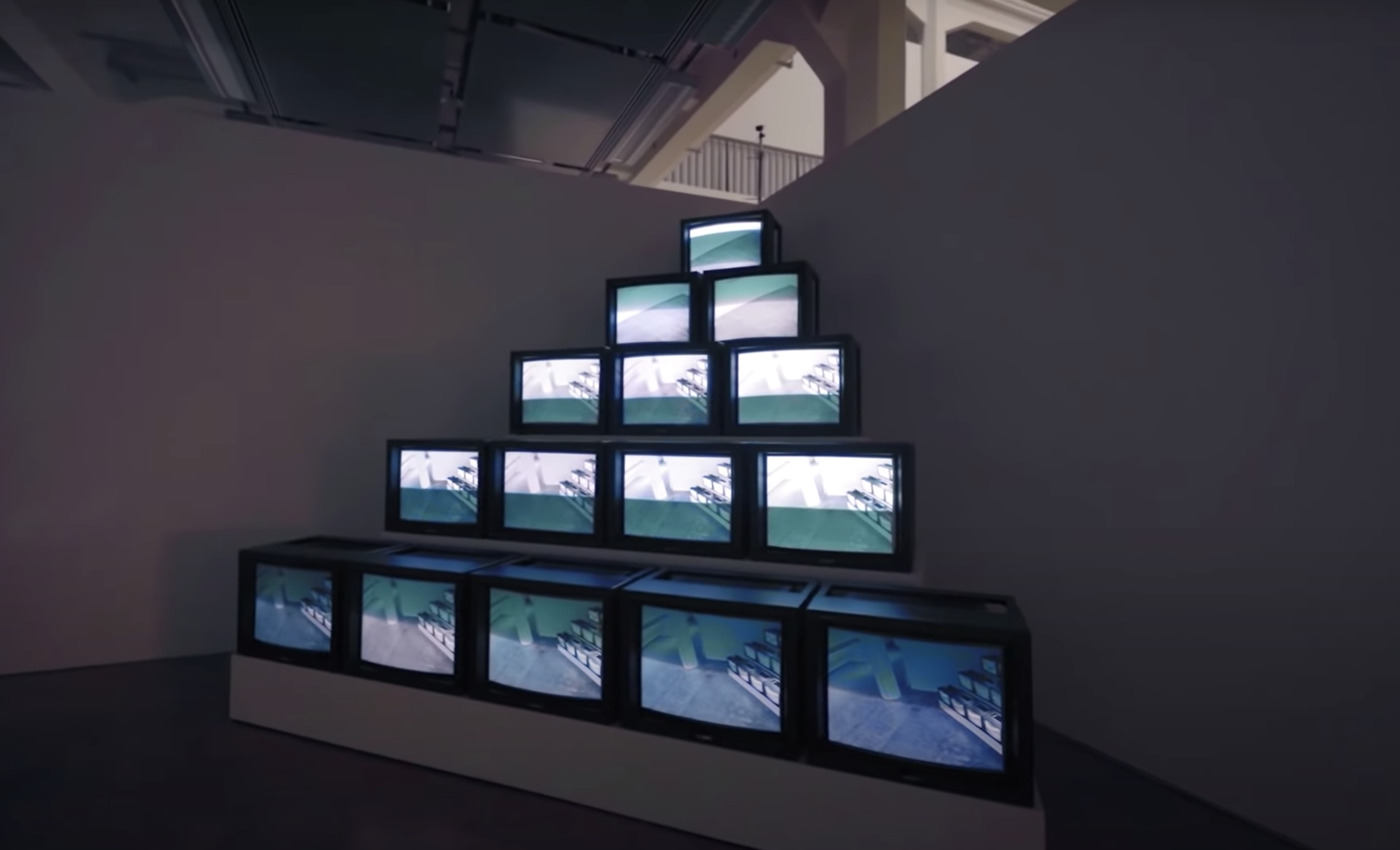 A pyramid-shaped art installation made up of old tv monitors, arranged in descending order of quantity from the base to th...