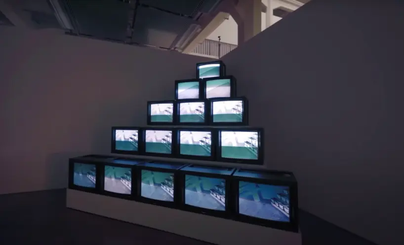 A pyramid-shaped art installation made up of old tv monitors, arranged in descending order of quantity from the base to th...