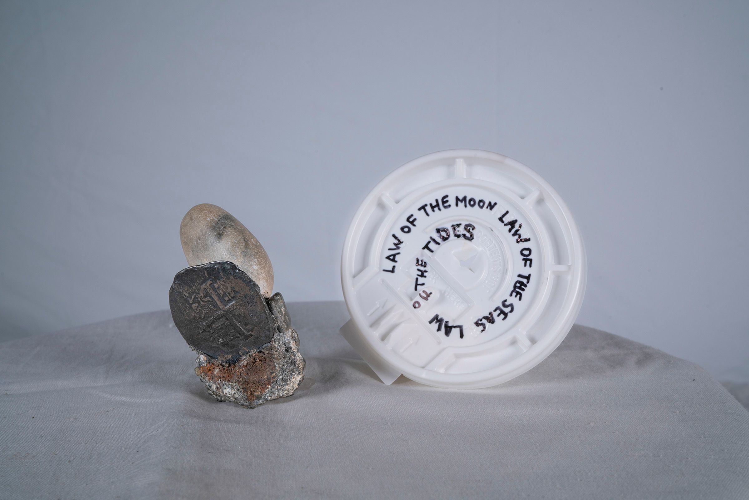 A white round plastic coffee lid with text written on it that reads "Law of the Moon Law of the Seas Law of the Tides" pla...