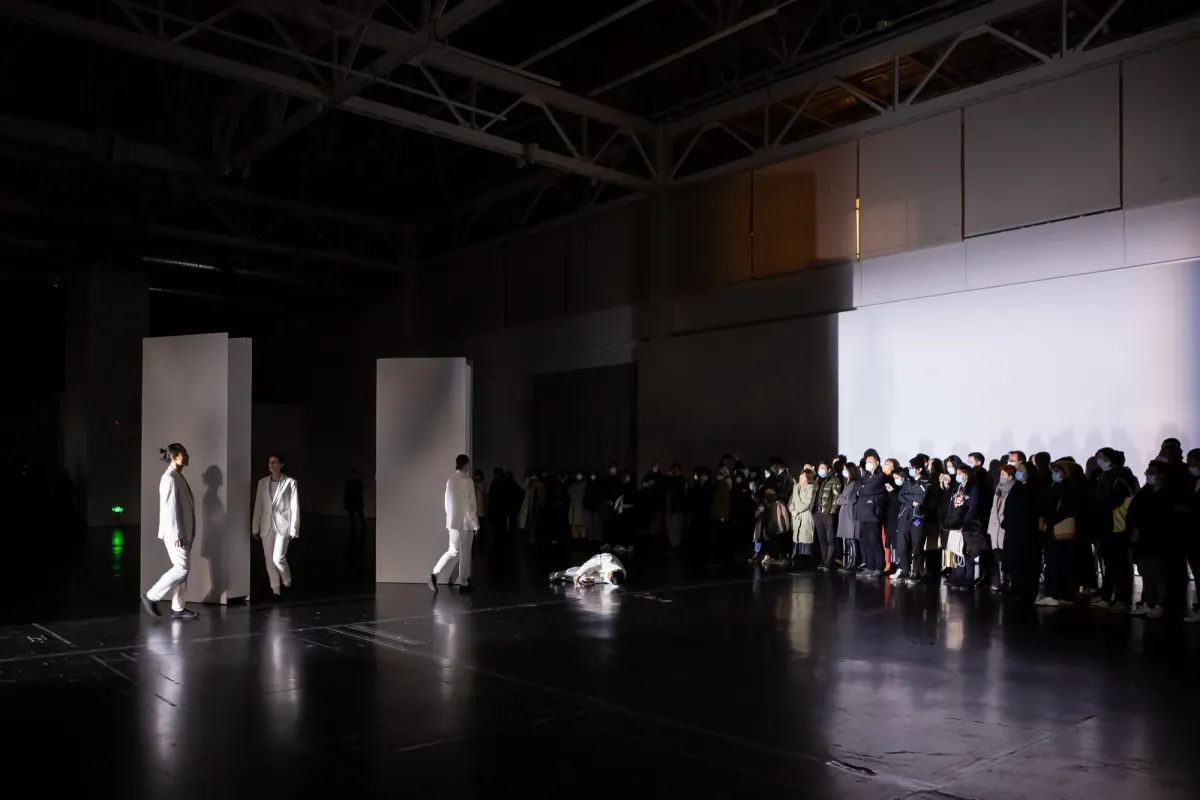A group of performers dressed in white carry out a performance in front of an assembled crowd at Yuz Museum.