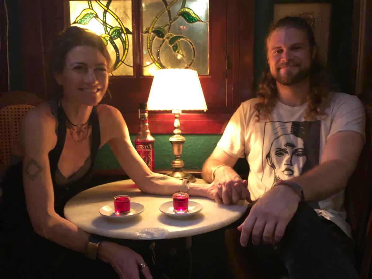 Two individuals clasp hands across a table in a bar.