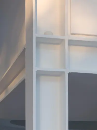 Close-up of a white sphere resting on a ledge where two white walls intersect, with soft light creating shadows.