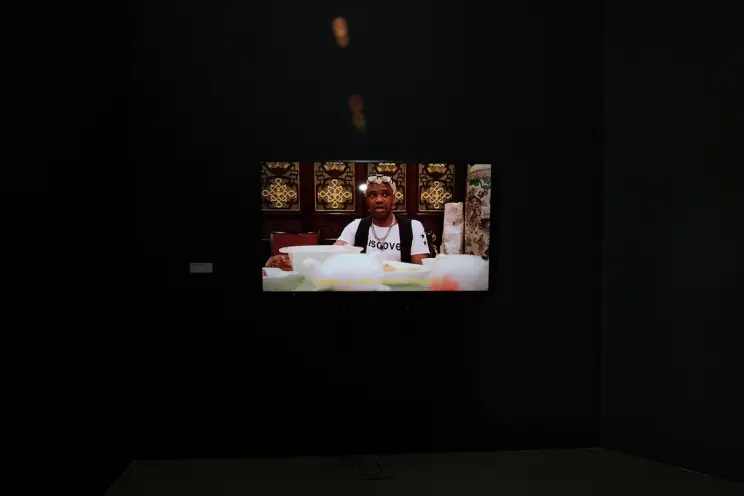 Video of a man at a table projected on a dark wall.