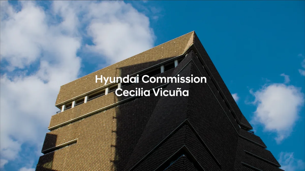 A daytime rooftop view of a building under a partly cloudy sky, with a sign reading "Hyundai Commission, Cecilia Vicuña" prominently displayed.