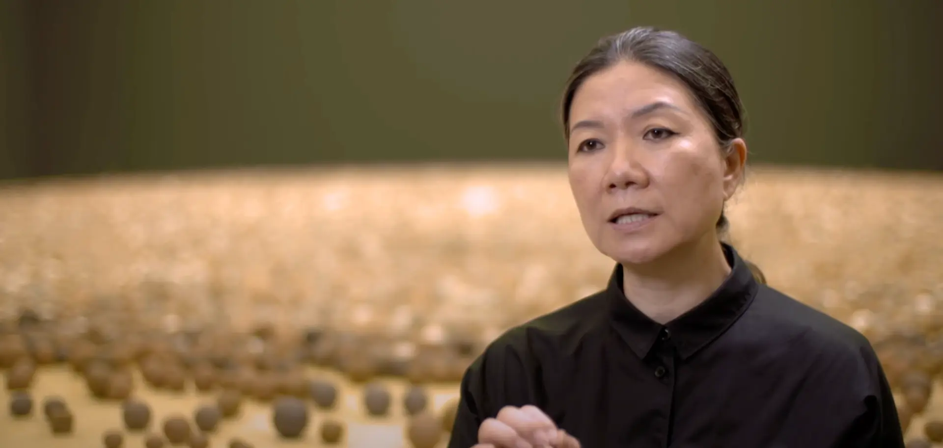 A person directly engaging with the camera, positioned against a softly blurred background.