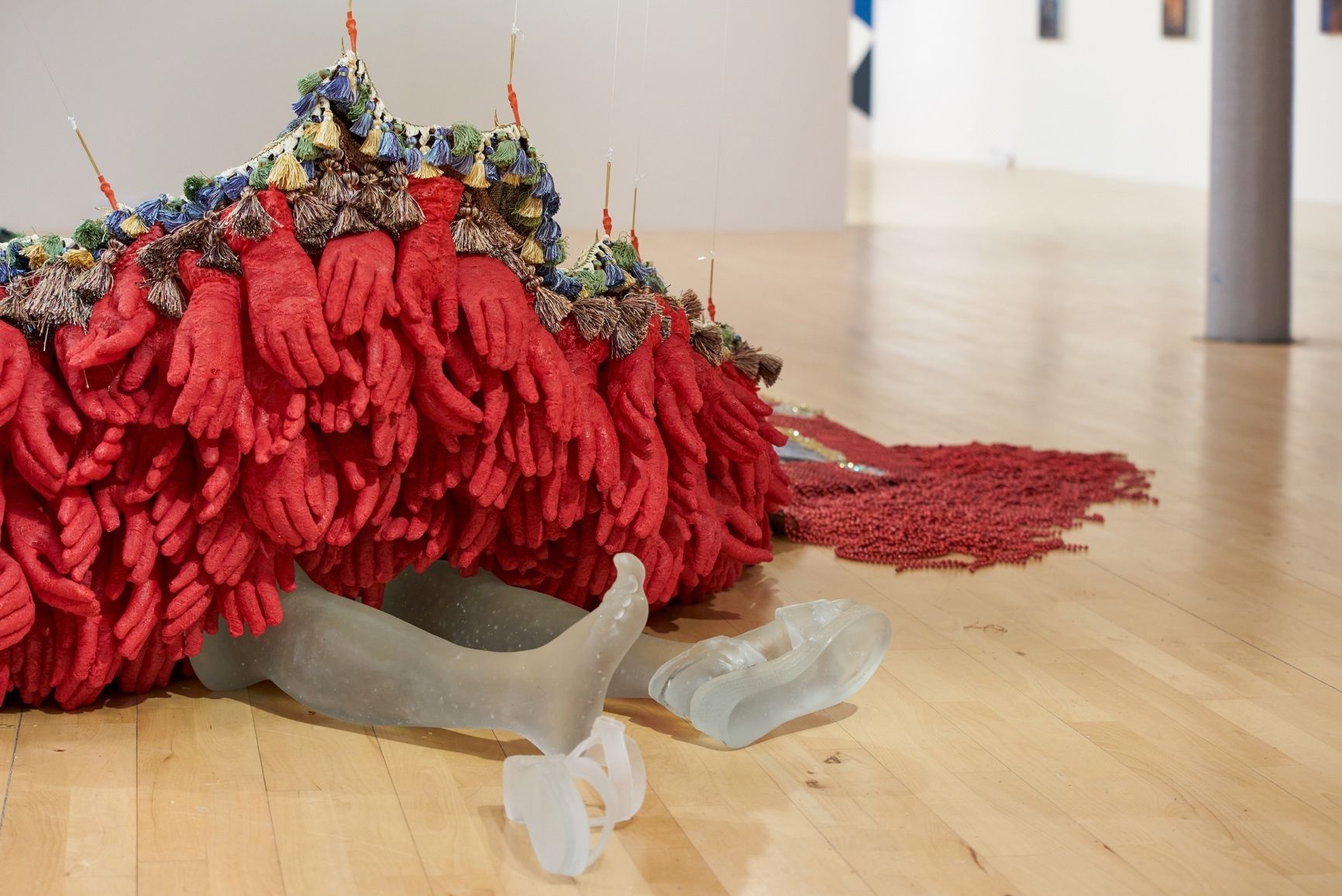 Transparent plastic legs arranged to resemble a person lying down, adorned with a pile of red gloves.