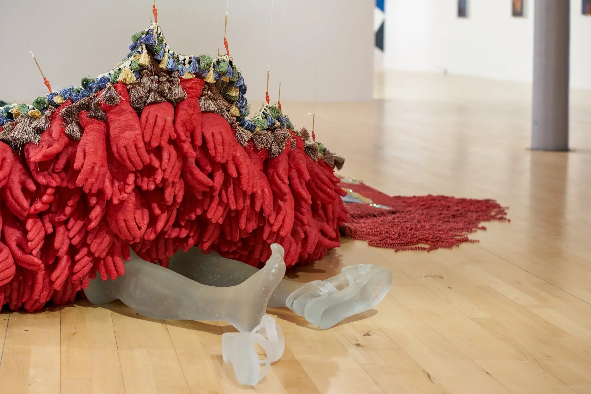 Transparent plastic legs arranged to resemble a person lying down, adorned with a pile of red gloves.