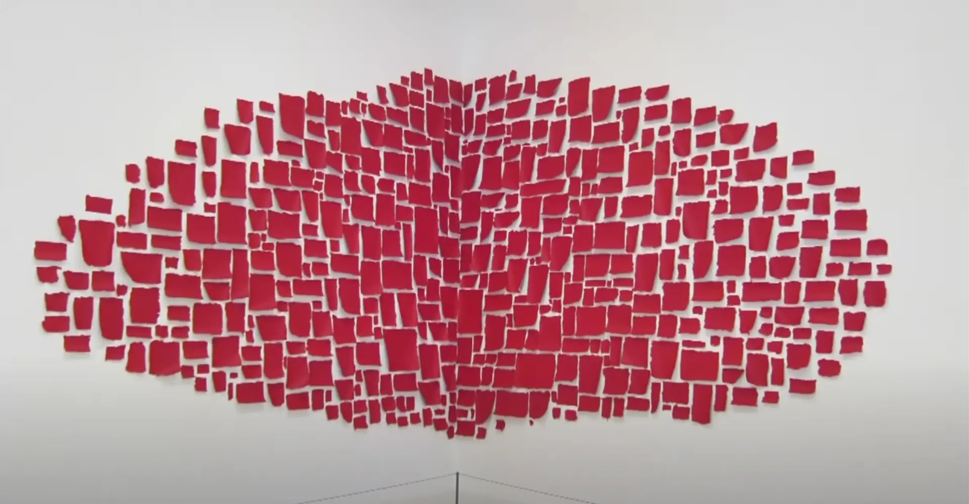 A pattern of red square and rectangular materials are affixed in the corner of a wall, creating a distinctive shape.