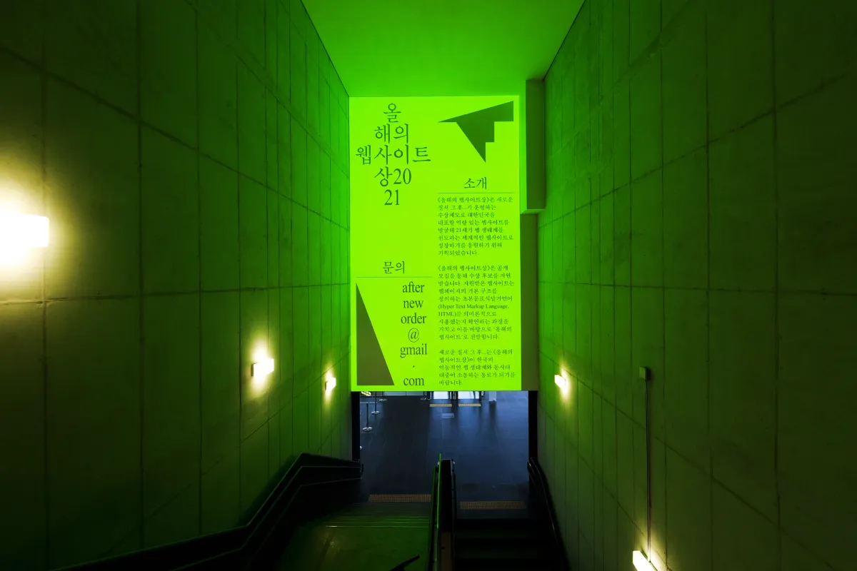 A bustling metro station bathed in green light, with an overhead sign glowing prominently.