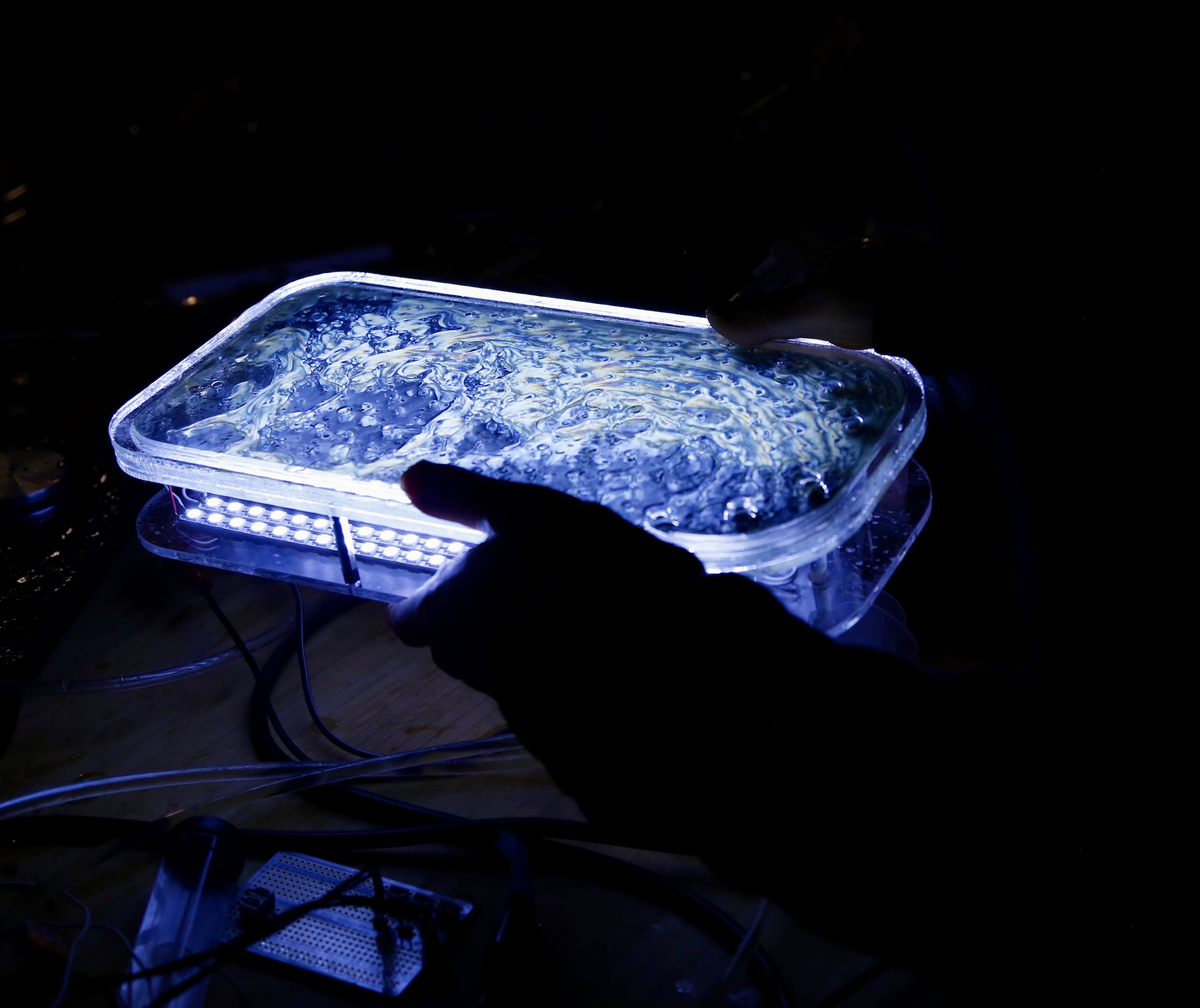 Hands holding a glowing blue glass box.
