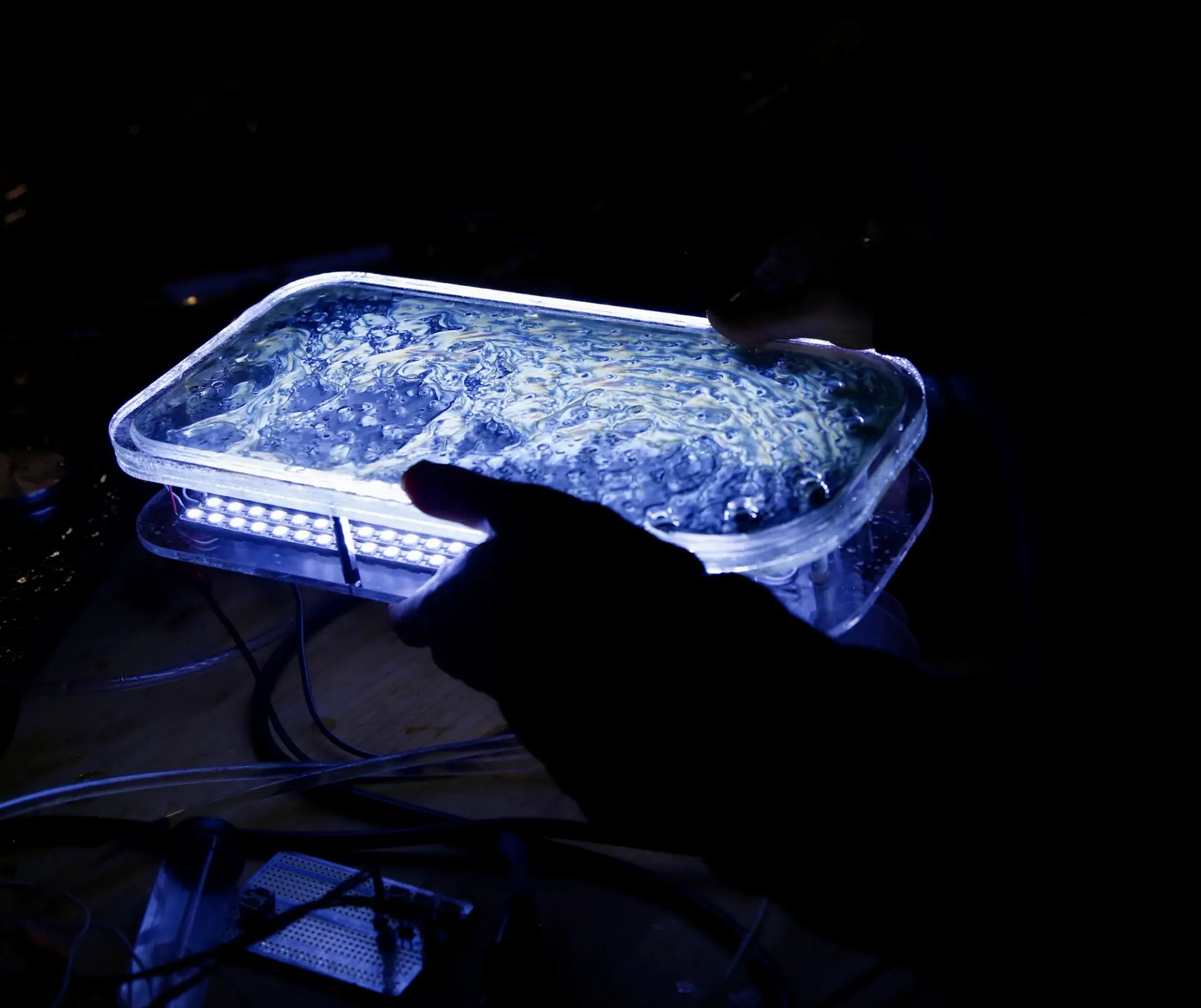 Hands holding a glowing blue glass box.