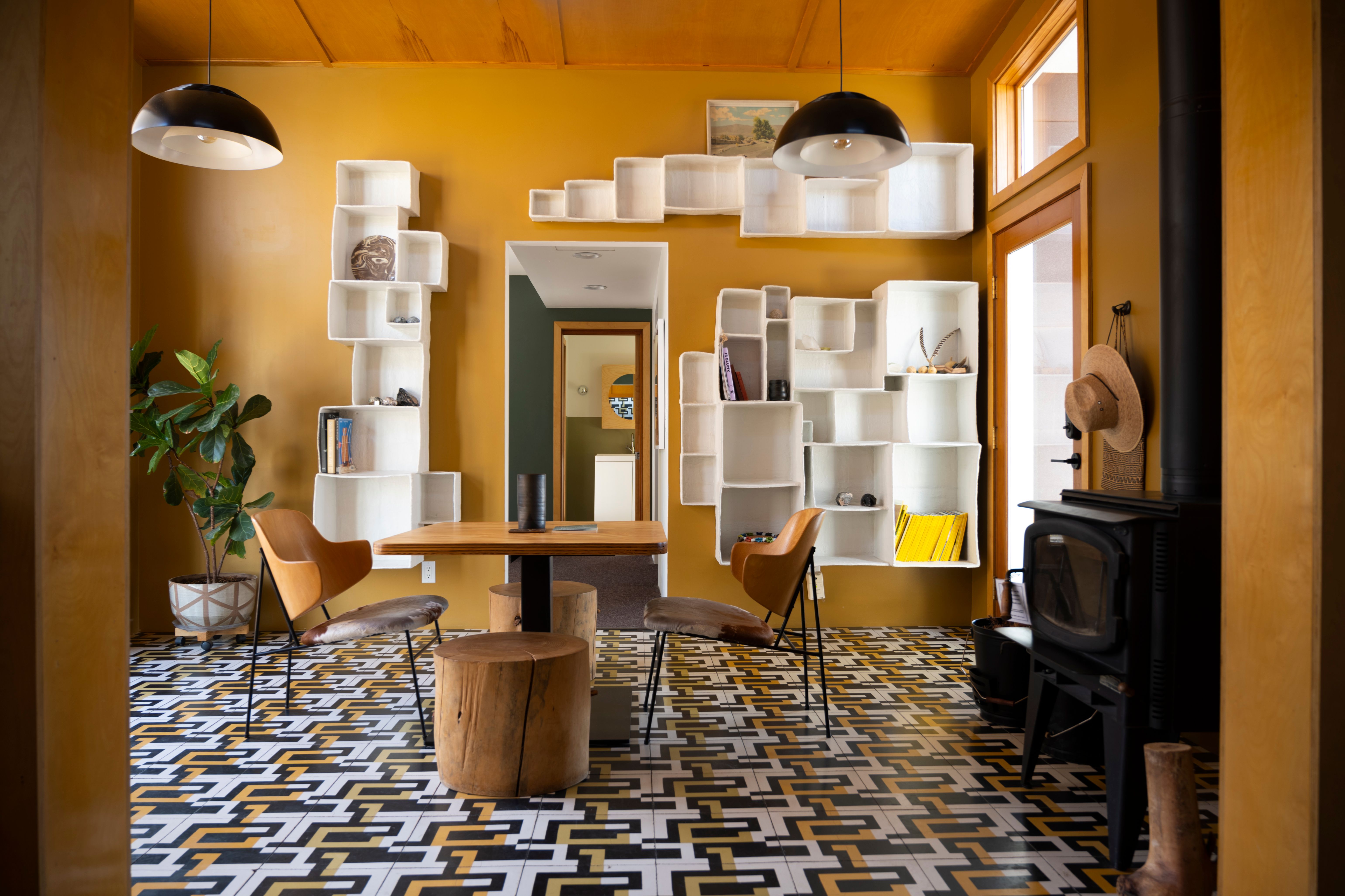 Modern room with geometric floor, unique shelving, wooden furniture, and a warm color palette.